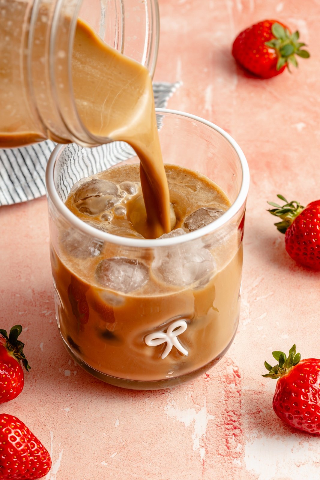 pouring a berry chantilly latte into a glass