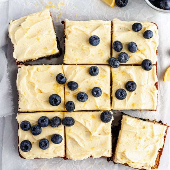 healthy lemon blueberry zucchini cake cut into nine slices topped with frosting