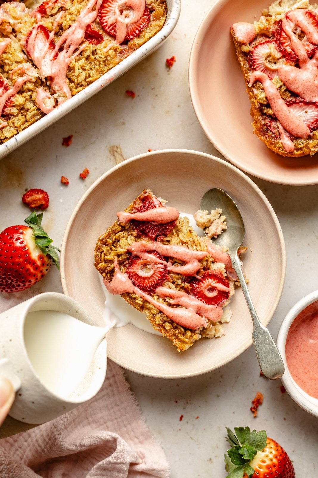 pouring milk into a bowl with a slice of strawberry baked oatmeal