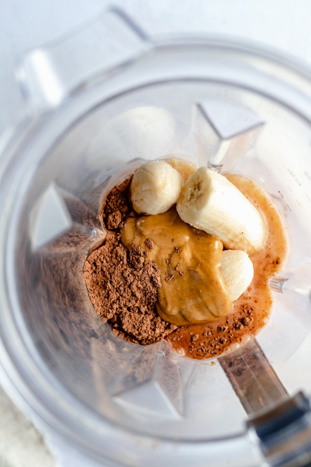 ingredients for a healthy chocolate peanut butter banana smoothie in a blender