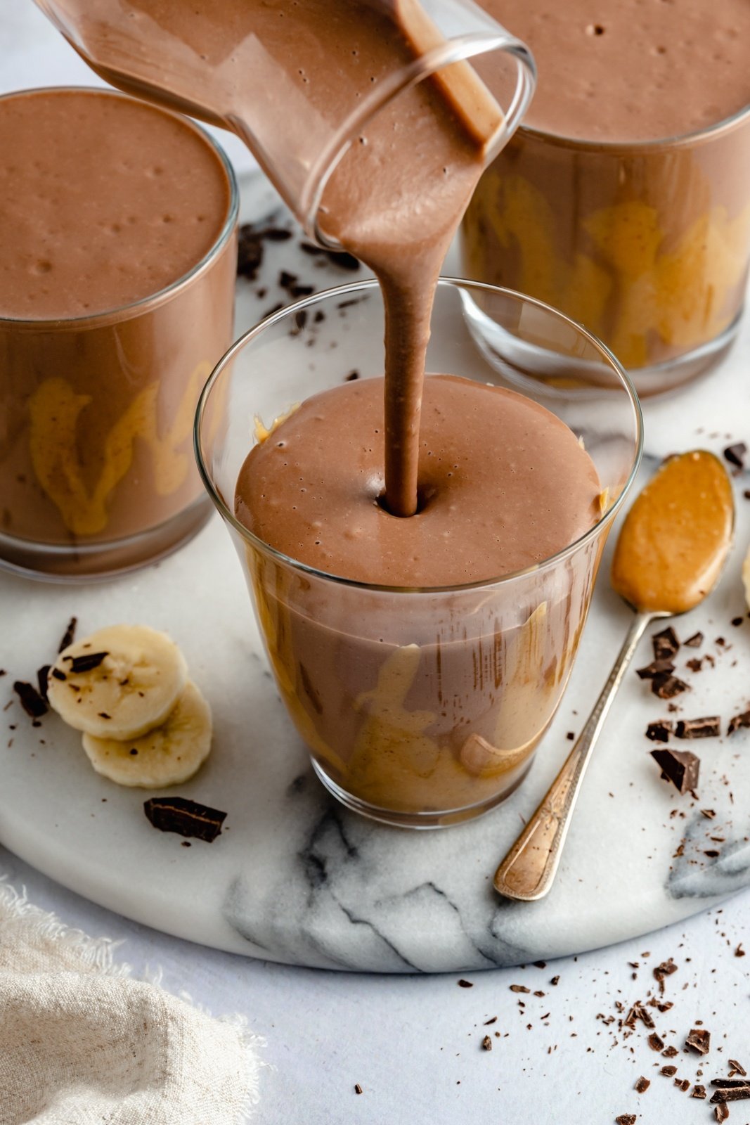pouring a healthy chocolate banana smoothie into a glass