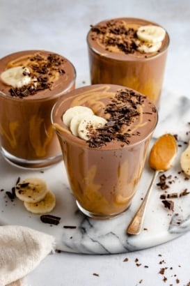 three chocolate peanut butter banana smoothies in glasses