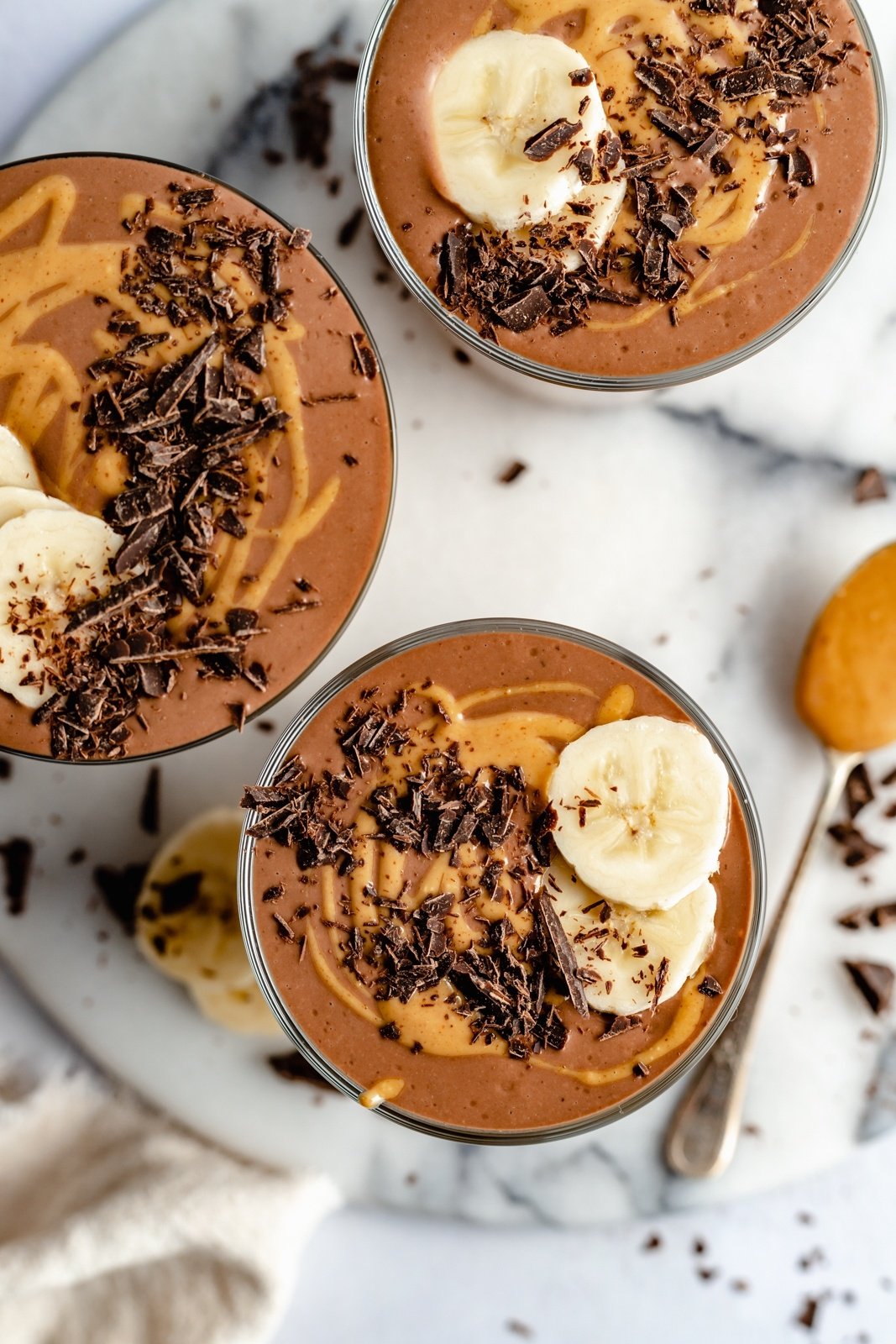 top-down view of three healthy chocolate banana smoothies in glasses