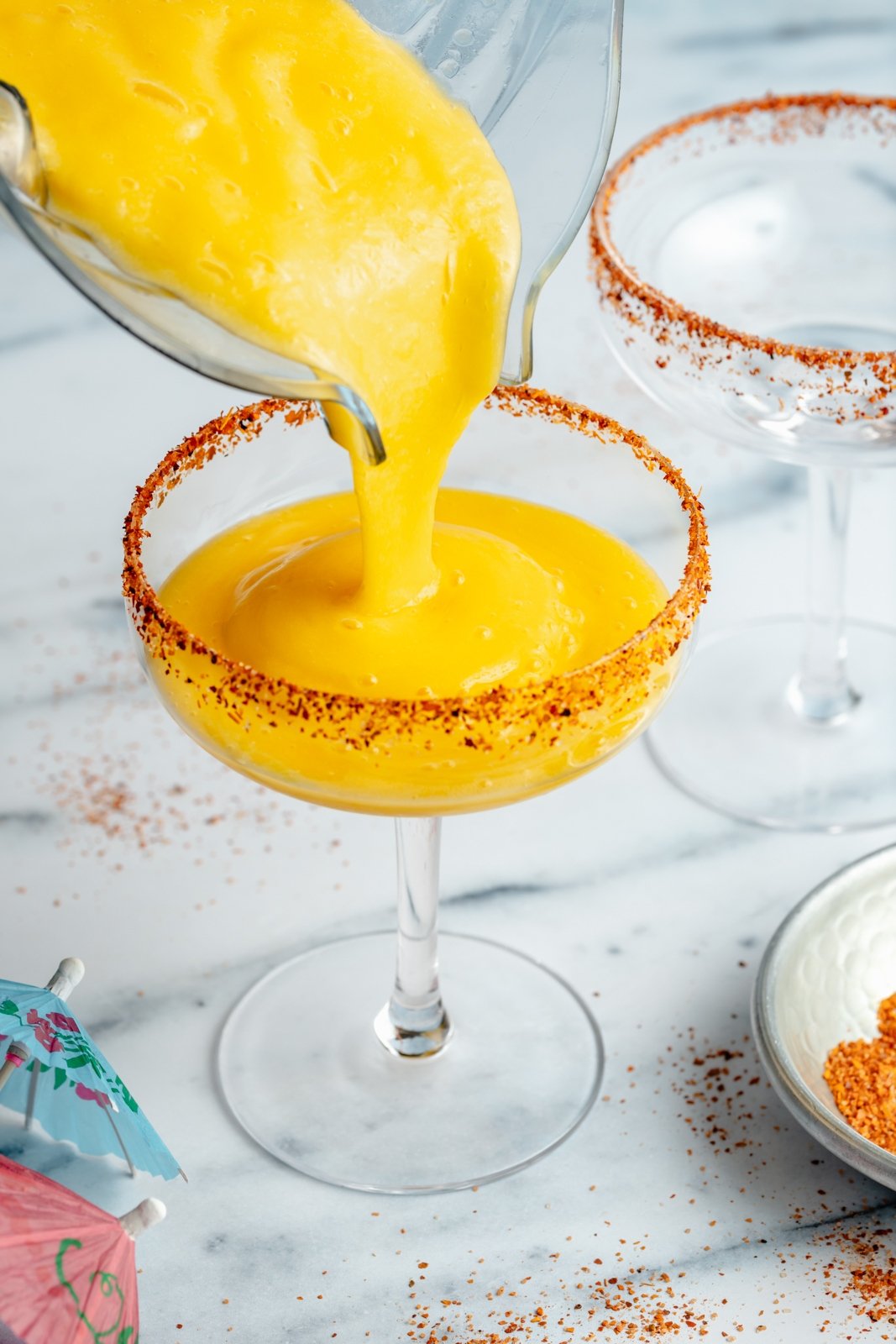 pouring a frozen mango margarita into a cocktail glass