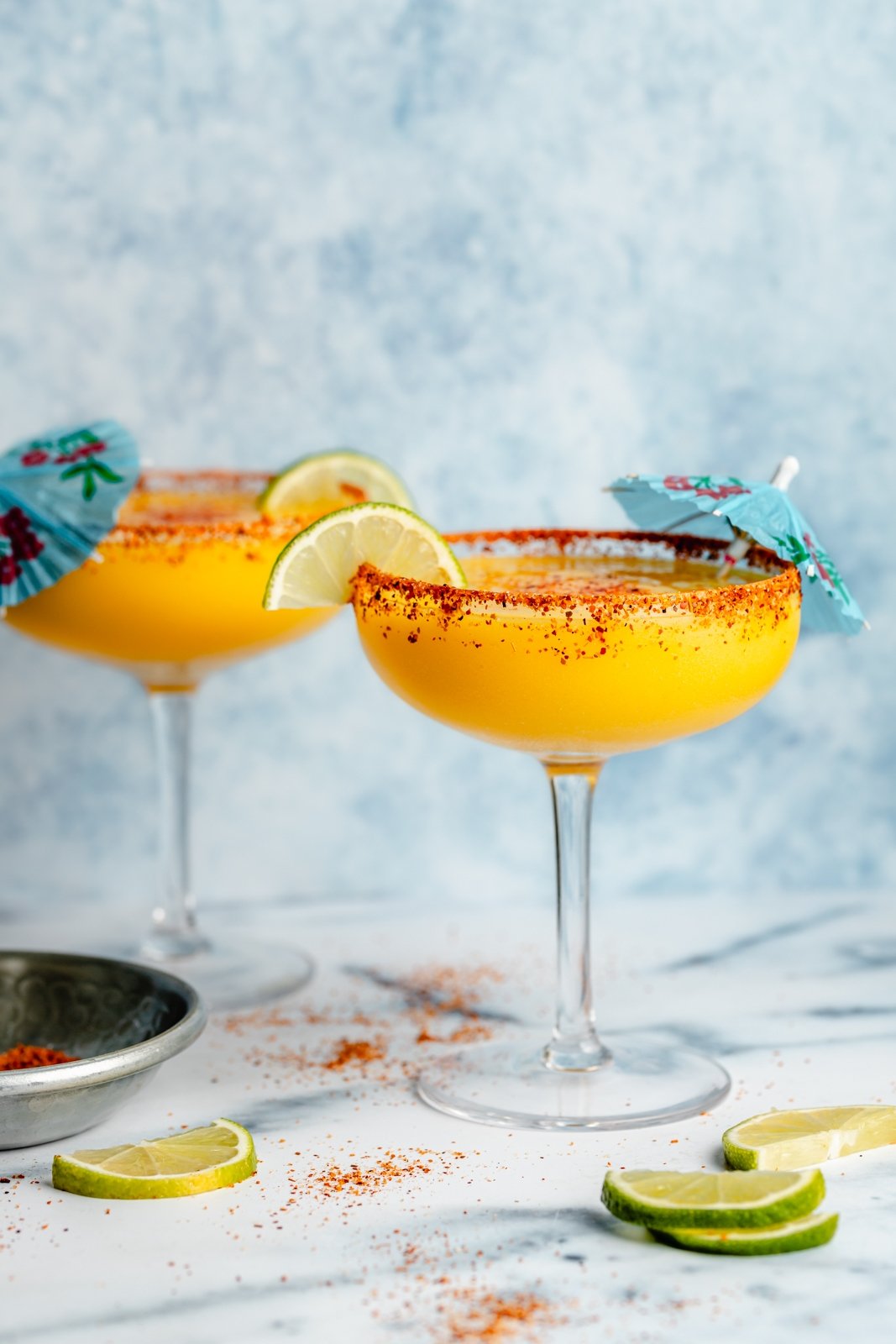 two frozen mango margaritas with blue umbrellas