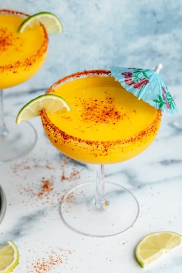frozen mango margarita in a glass with a blue umbrella