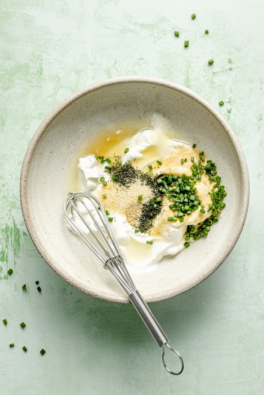 ingredients for healthy greek yogurt ranch dressing in a bowl with a mini whisk