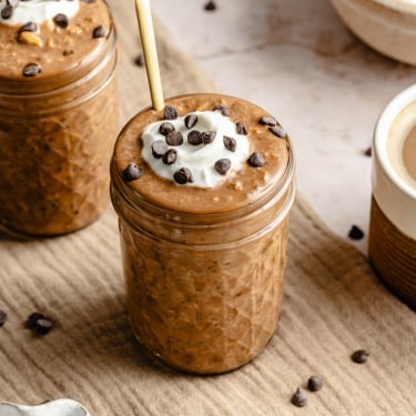 coffee overnight oats in two jars topped with yogurt and chocolate chips