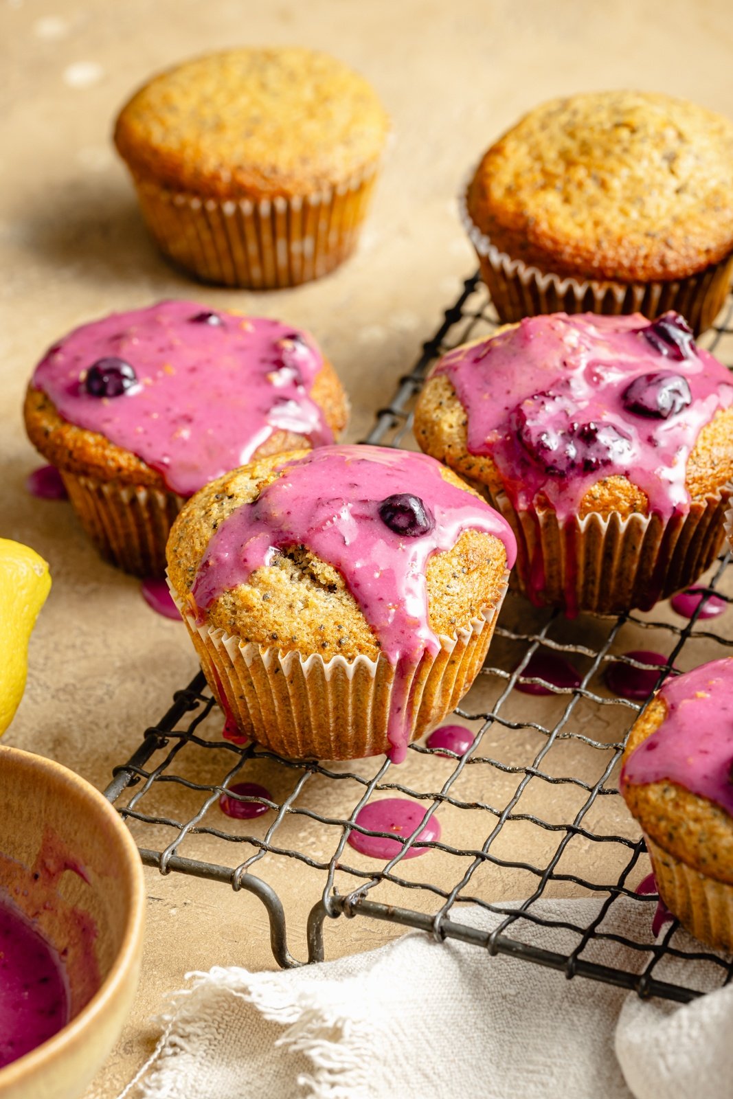 healthy lemon poppy seed muffins with blueberry glaze on a wire rack