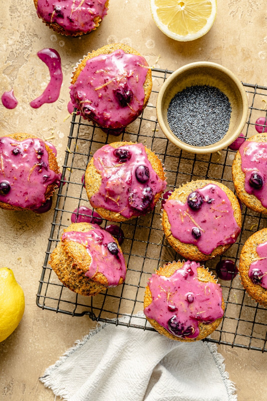 lemon poppy seed muffins topped with blueberry glaze on a wire rack