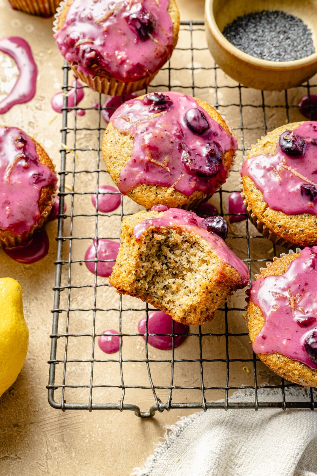 lemon poppy seed muffins with blueberry glaze on a wire rack