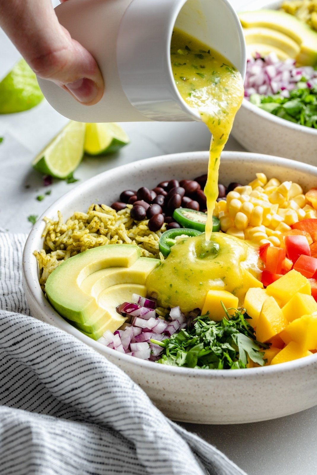 pouring dressing onto a green rice burrito bowl