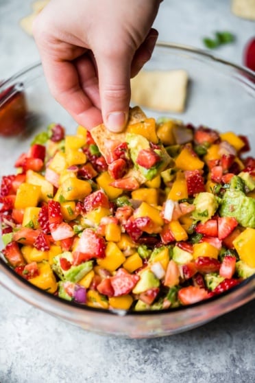 dipping a chip into Avocado Strawberry Mango Salsa