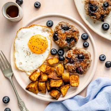 blueberry breakfast patties on a plate with a fried egg and potatoes