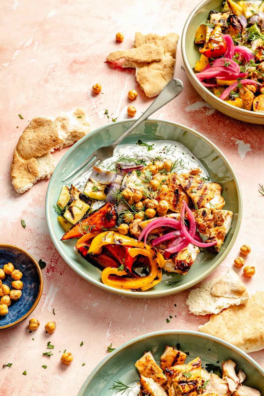 grilled mediterranean chicken and vegetables in bowls with tzatziki, pita bread, and chickpeas