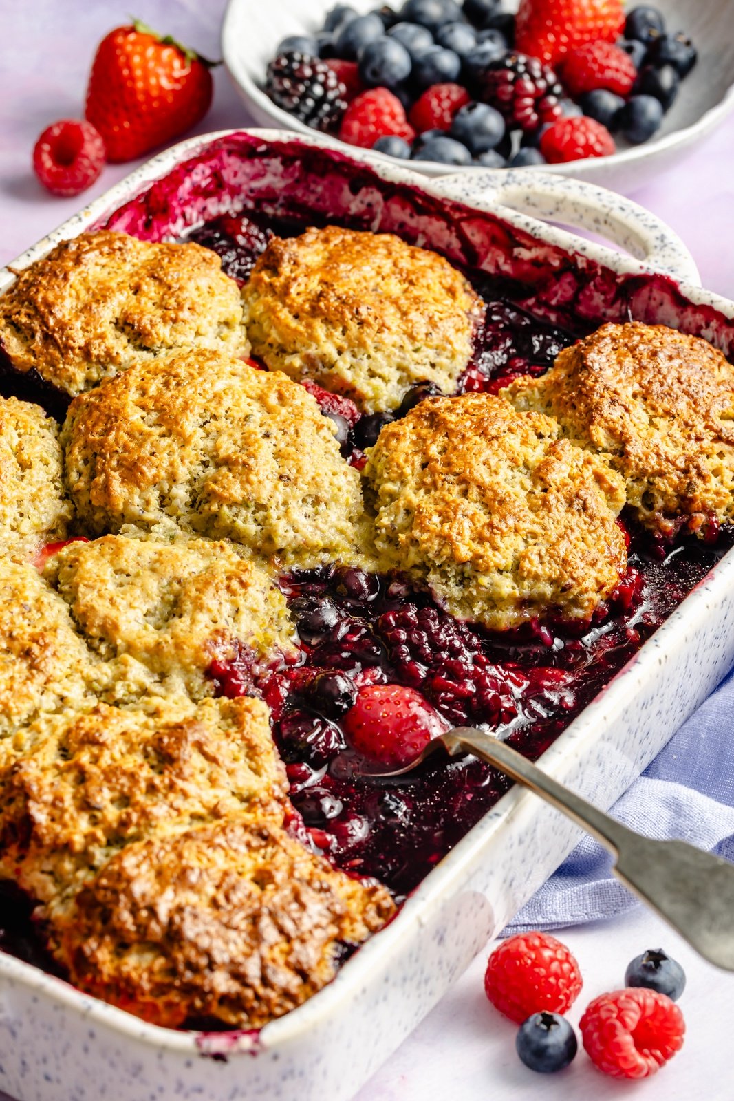 easy berry cobbler in a baking pan with a spoon