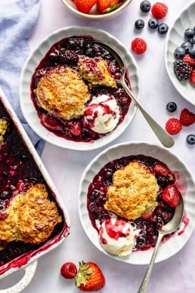 berry cobbler in two bowls with vanilla ice cream