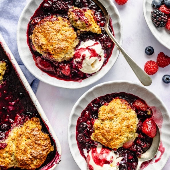 berry cobbler in two bowls with vanilla ice cream