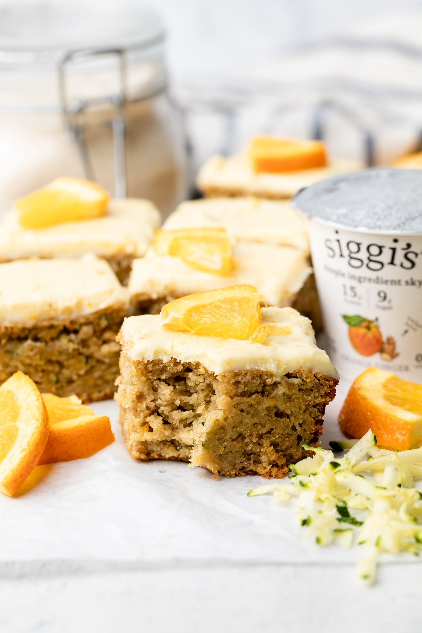 piece of orange zucchini cake on parchment paper next to a container of yogurt