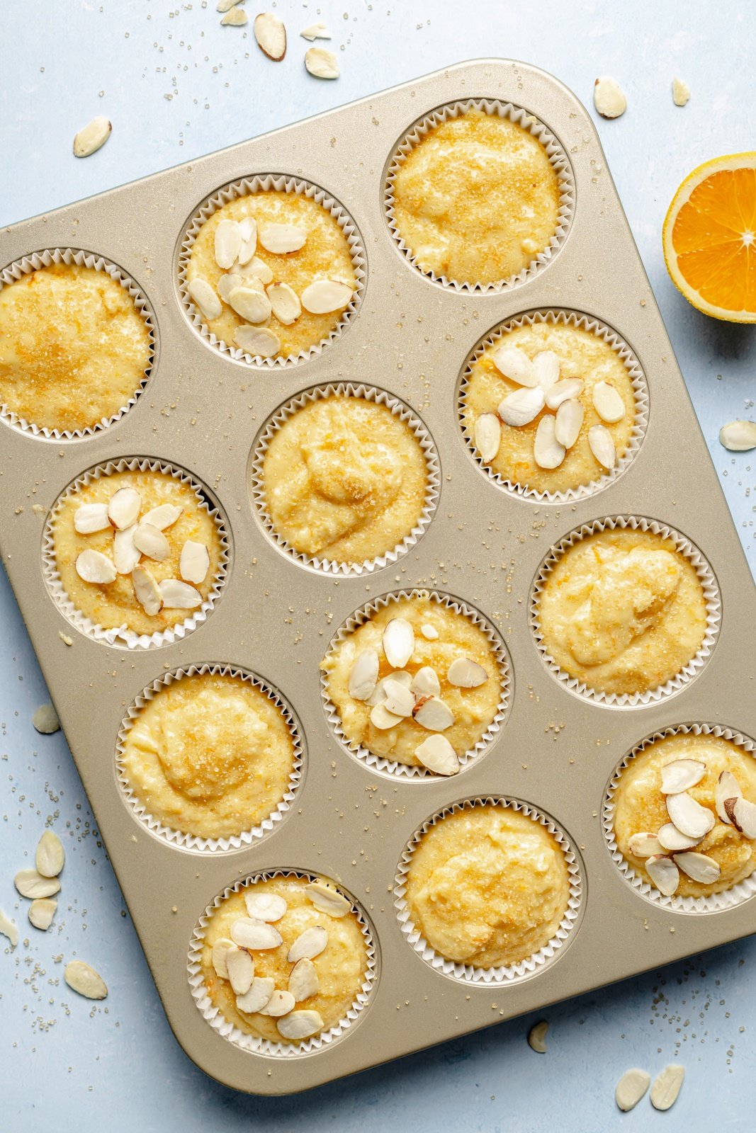 unbaked orange muffins in a muffin tin