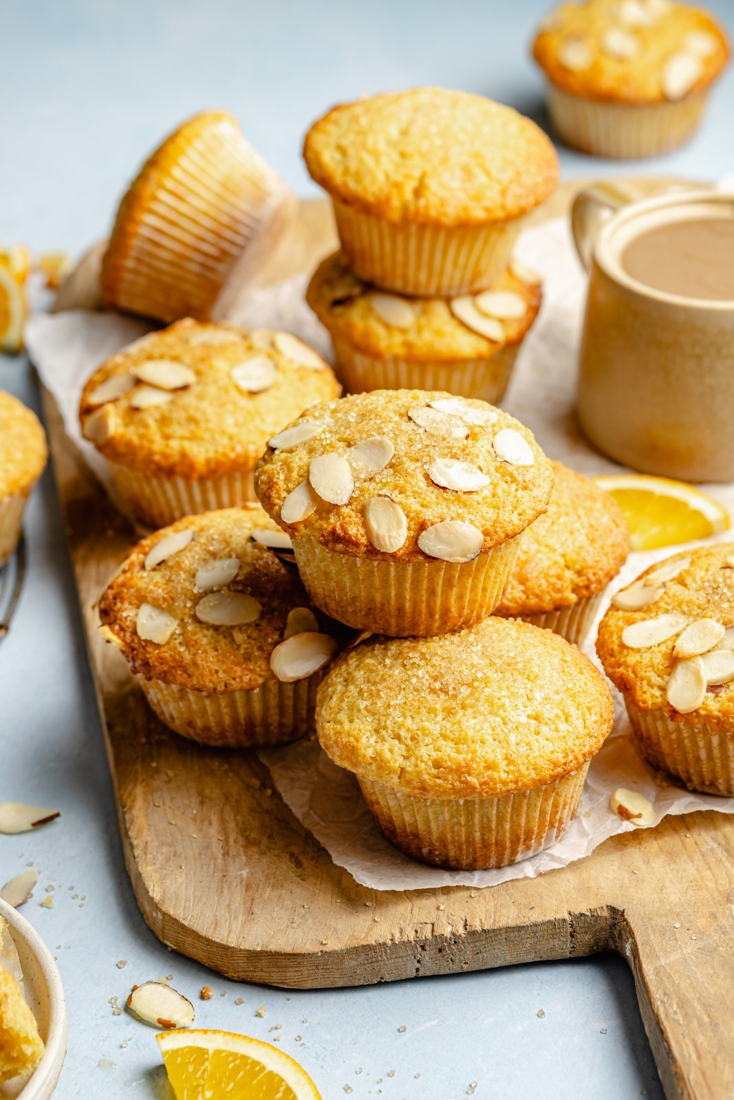 moist orange muffins topped with sliced almonds on a wooden board