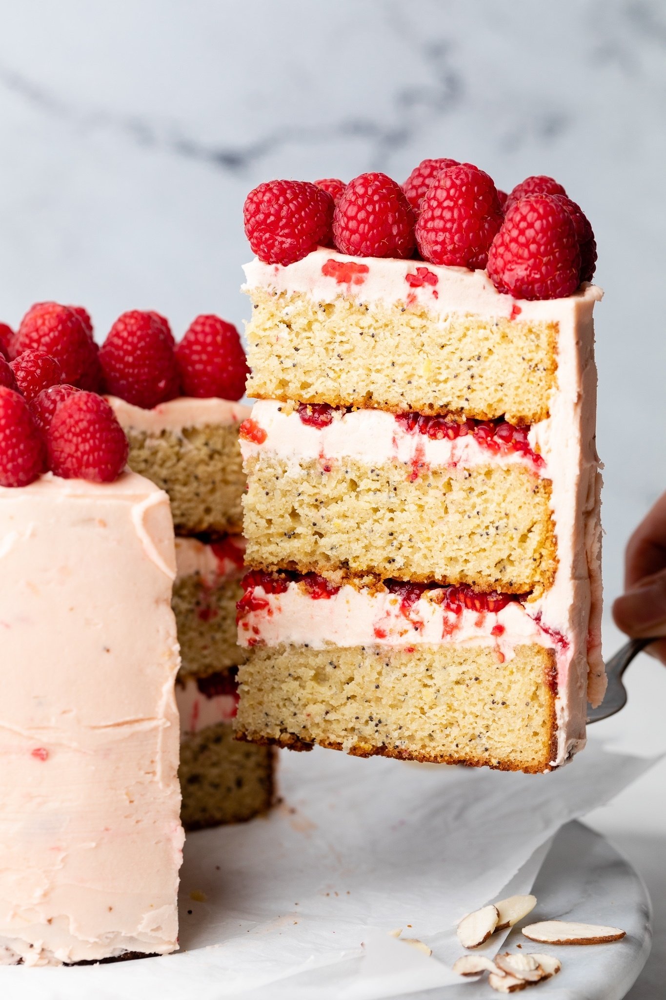 pulling a slice of gluten-free lemon raspberry cake out of the cake
