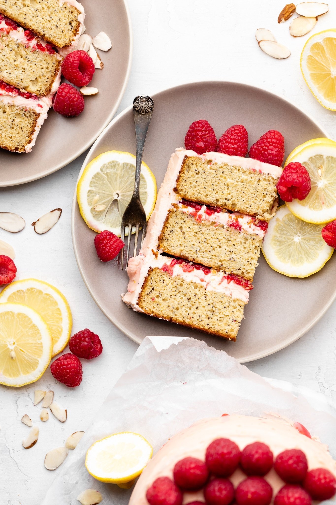 lemon raspberry cake slices on plates next to fresh raspberries