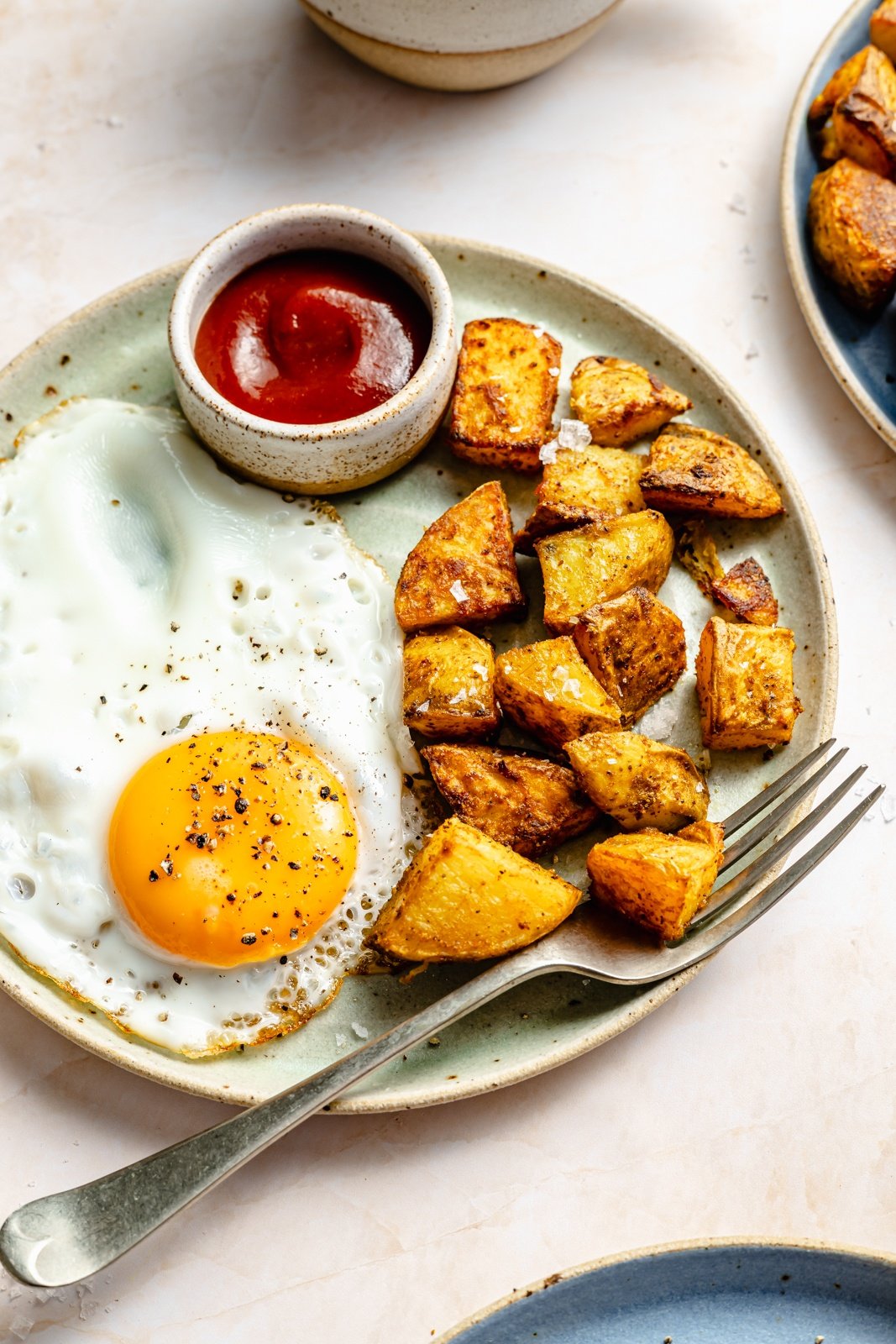 breakfast potatoes, ketchup, and an egg on a plate