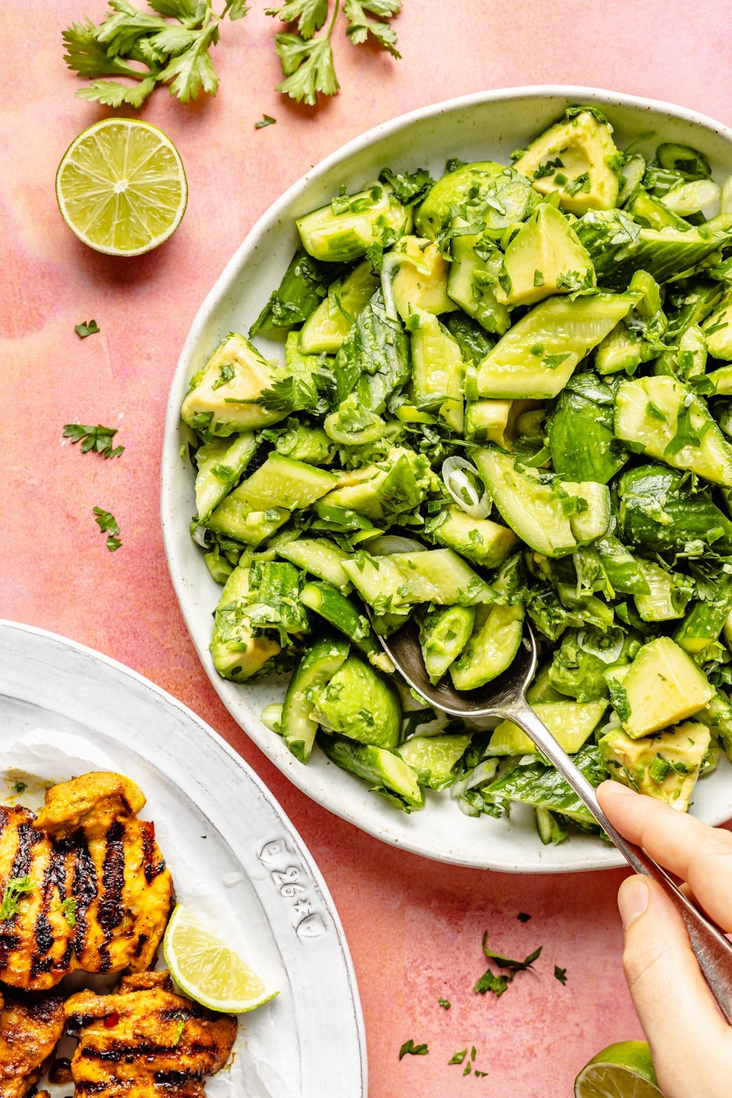smashed cucumber salad in a bowl next to grilled turmeric chicken