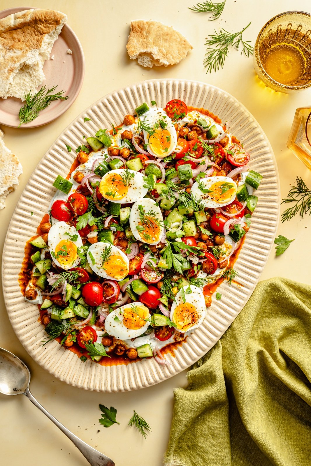 spiced chickpeas and eggs with salad and yogurt on a platter