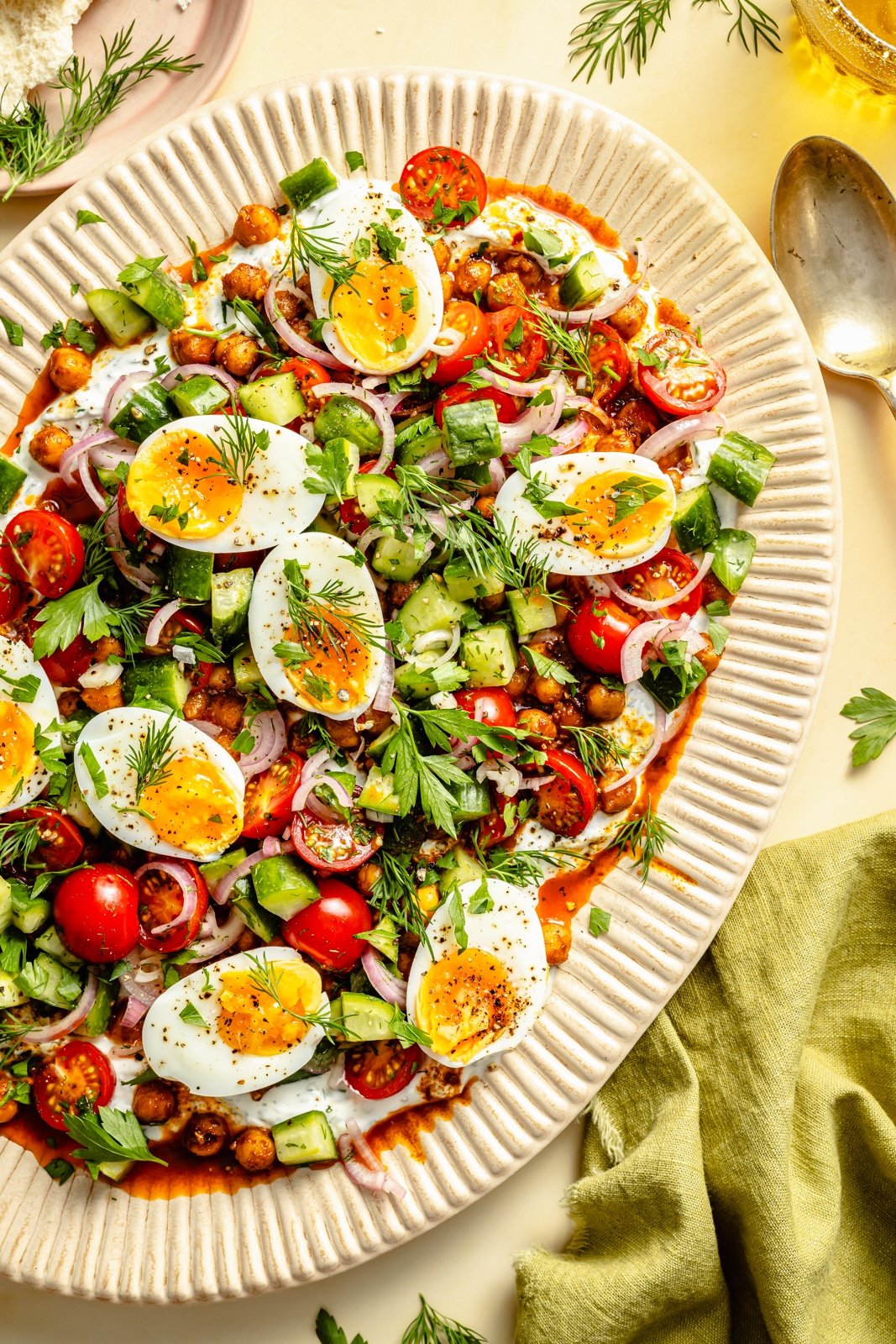 spiced chickpeas and eggs on a platter with vegetables and yogurt