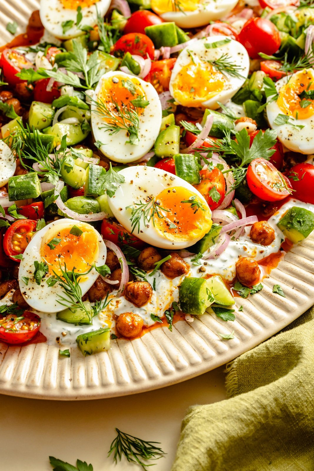 platter of spiced chickpeas with eggs, salad, and garlic herb yogurt
