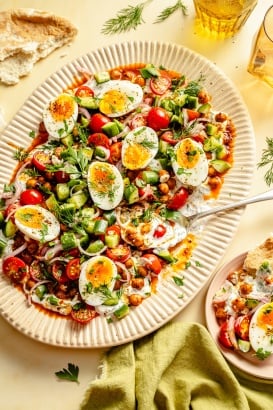 spiced chickpeas and eggs with cucumber salad and yogurt on a platter