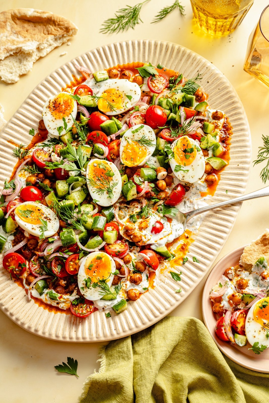 spiced chickpeas and eggs on a platter with cucumber salad and yogurt