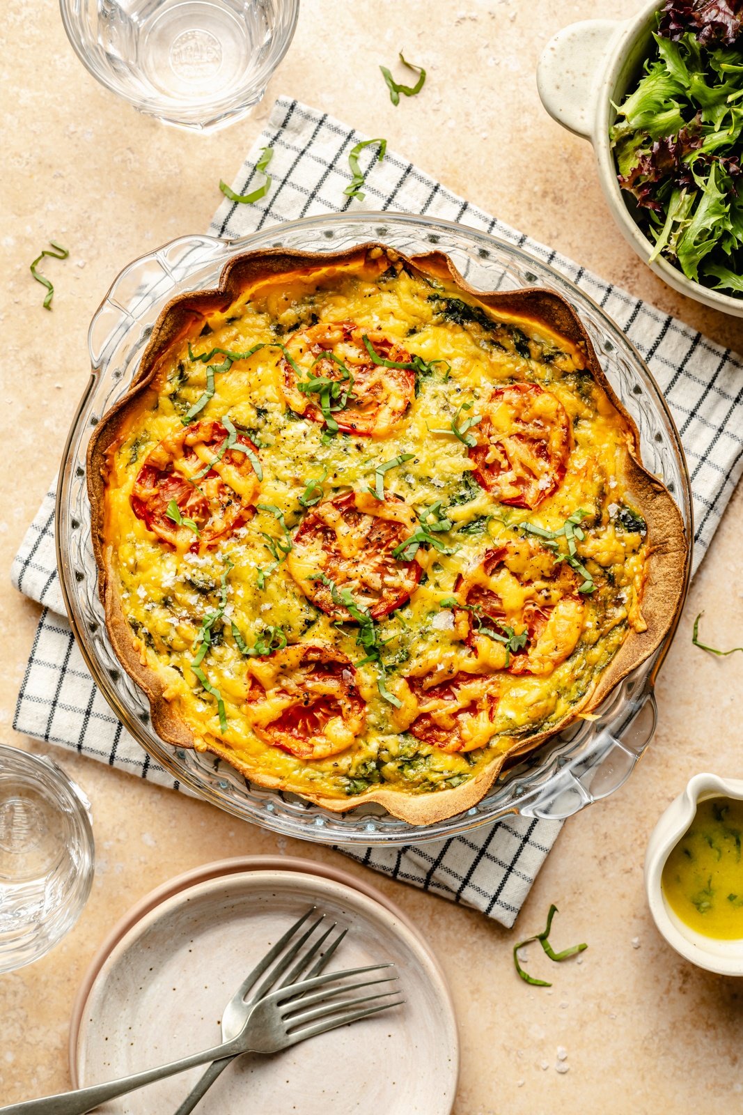 easy tortilla quiche with spinach, tomato and basil in a pie pan