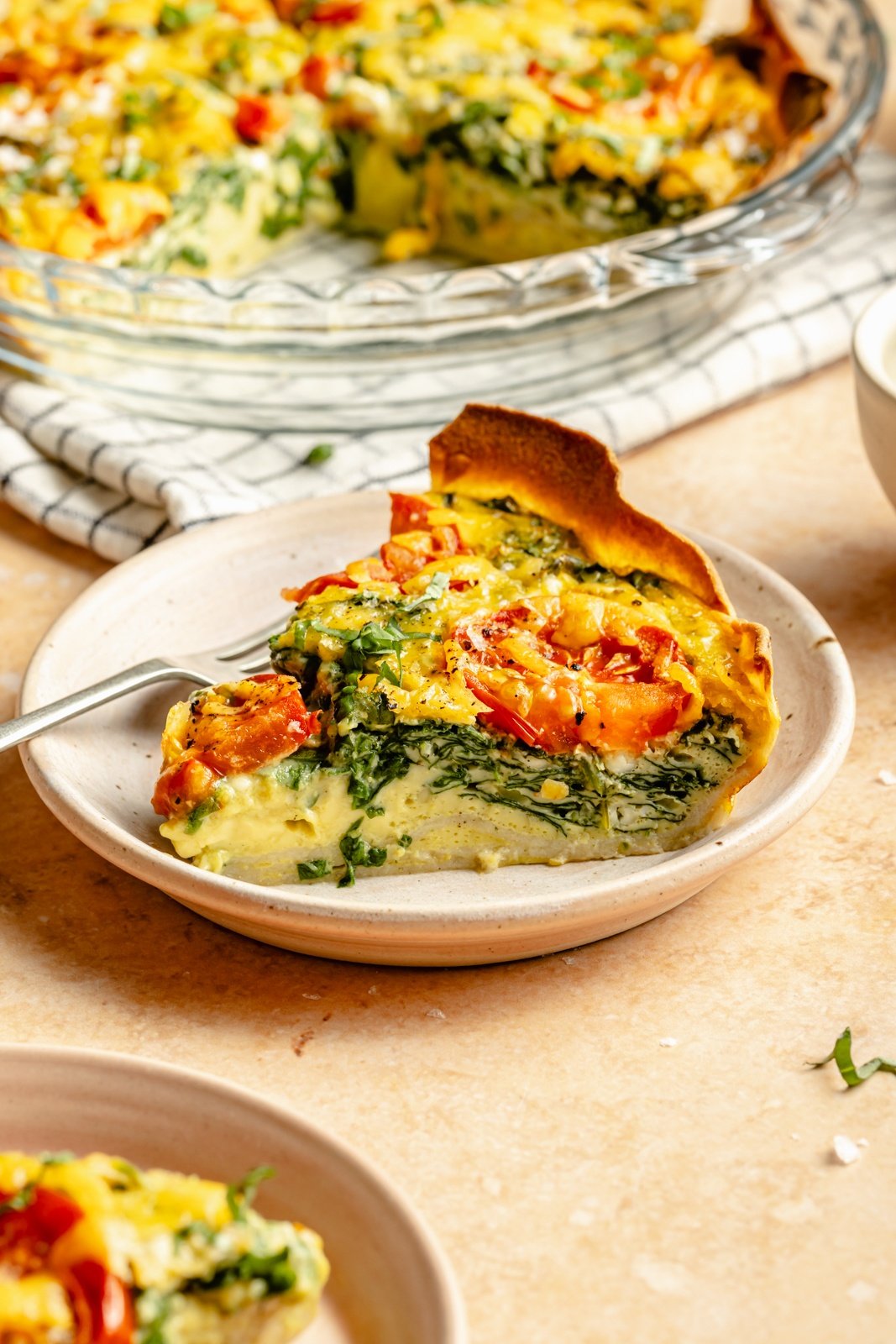 slice of tortilla quiche with tomato, spinach, and basil on a plate